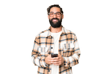 Young man with beard over isolated chroma key background sending a message with the mobile