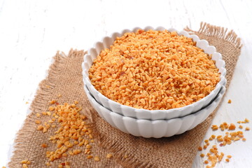 Bowl of roasted crushed peanuts isolated on white background