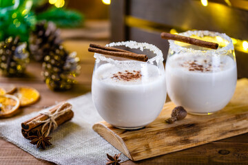 Christmas drink from raw eggs egg-nog on a wooden surface with a bokeh of rustic garlands