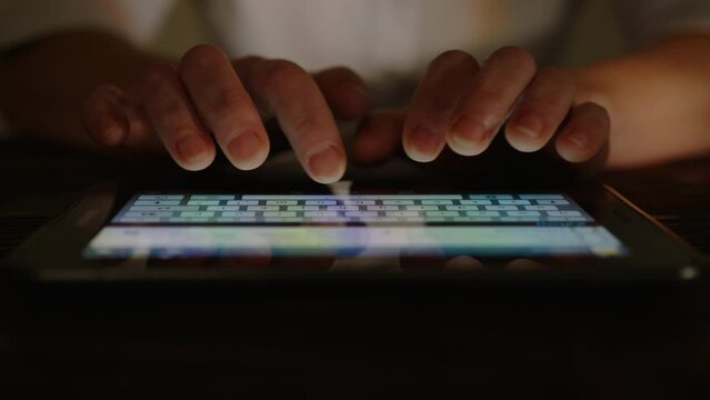 Human hands typing text on tablet touch screen keyboard 