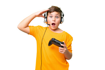 Little caucasian kid playing with a video game controller over isolated chroma key background with surprise expression