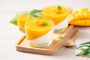 Delicious double colored mango panna cotta mousse pudding on wooden table background. - obrazy, fototapety, plakaty