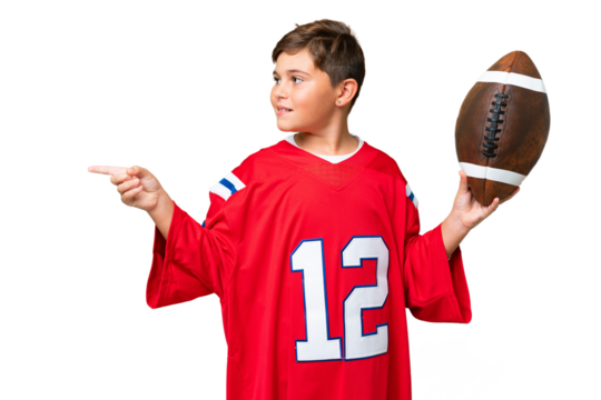 Little caucasian kid playing rugby over isolated chroma key background pointing to the side to present a product