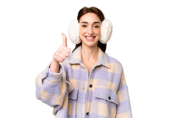 Young caucasian woman wearing winter muffs over isolated chroma key background with thumbs up...