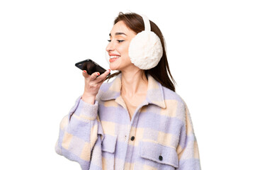 Young caucasian woman wearing winter muffs over isolated chroma key background keeping a...