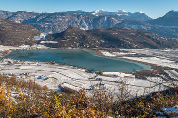 View on the famous and popular lake of Caldaro on the South Tyrolean Wine Route near Bolzano in South Tyrol, norther Italy, Europe. Winter landscape with snow.