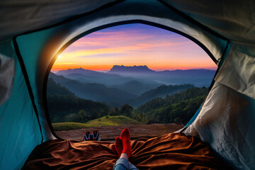 Woman cross leg on blanket in camping tent with sleeping bags on mountain hill. view from inside...