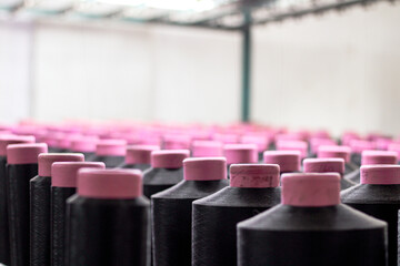 group of textile cones of black kota yarn isolated on c creel stand for warping thread. textile weaving factory. selective focus. - obrazy, fototapety, plakaty