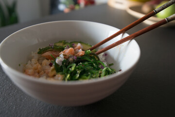 Close up of a bowl with salmon poke and chopsticks.