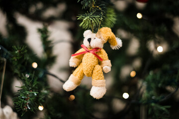 Holiday spirit and Christmas decorations. Christmas style little teddy bear hanging on a Christmas tree.