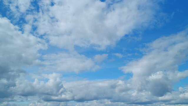 Summer sky. Cirrus and cumulus on different layers clouds on bright blue sky. Wispy cirrus clouds pass over blue sky in nature. Timelapse.
