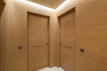 Soft light from niche under ceiling illuminates doors and walls in common corridor. Interior is...