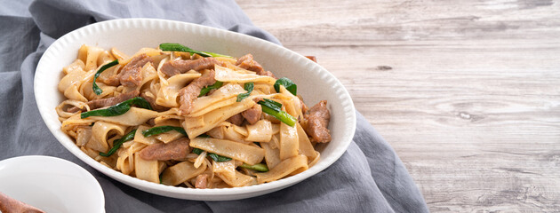 Delicious stir-fried Taiwanese Hakka flat rice noodles on white background.
