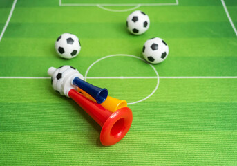 Football soccer triple fan trumpet with toy football on green grass © xiaoliangge