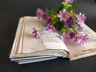 book and flowers on black background