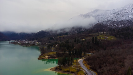 Aerial drone view of Lake Barcis, mountains with snow and fog, emerald lake and autumn trees