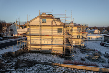 Fototapeta premium Reconstruction of residential building in European village, working scaffold, aerial view
