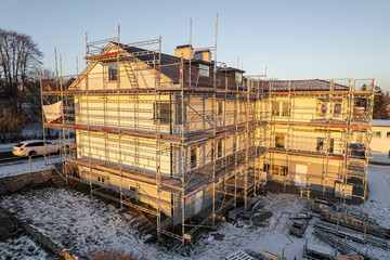 Reconstruction of residential building in European village, working scaffold, aerial view