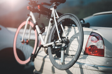 Fototapeta na wymiar Bike on the bike carrier at the back of the red off-road vehicle, blurry car background. 