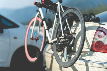 Fototapeta na wymiar Bike on the bike carrier at the back of the red off-road vehicle, blurry car background. 