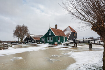 Winter landscape with frozen canal and traditional wooden house in Zaanse Schans, Netherlands - 554673052