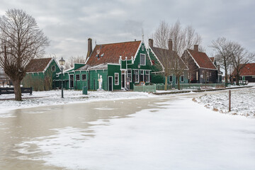 Winter landscape with frozen canal and traditional wooden house in Zaanse Schans, Netherlands - 554673090