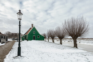 Winter landscape with frozen canal and traditional wooden house in Zaanse Schans, Netherlands - 554673211
