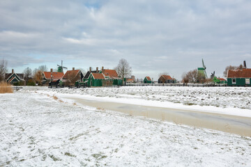 Winter landscape with frozen canal and traditional wooden house in Zaanse Schans, Netherlands - 554673499