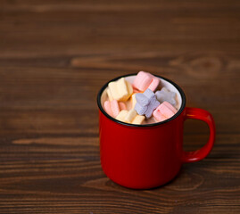 Red cup with cocoa and marshmallows on wooden background