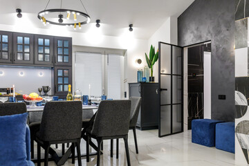 A modern living room with a blue sofa and a fixed table. Ceiling with wooden beams. Open space