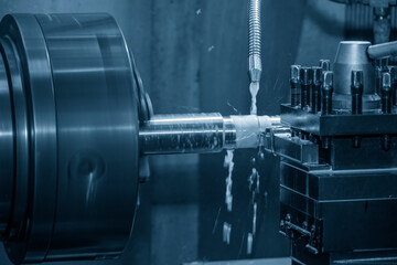 The lathe machine cutting the metal shaft parts with coolant method.