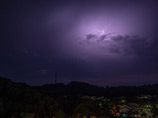 Lightning strikes during thunder storm over a hill view during night