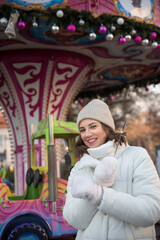 fair . attractions , carousel . girl dressed in a white jacket and a white hat. the girl smiles. .girl rejoices. emotions. Celebrating Christmas outdoors.