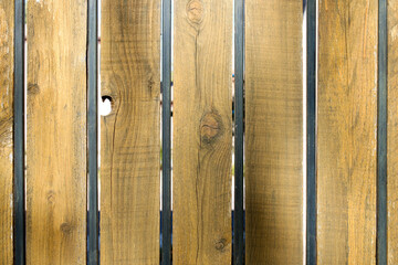 Light brown weathered wooden planks and painted in black metal frame segments of backyard gate,...