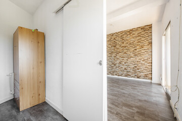 An empty room with a wooden cabinet in one corner, a white wooden sliding door leading to another...