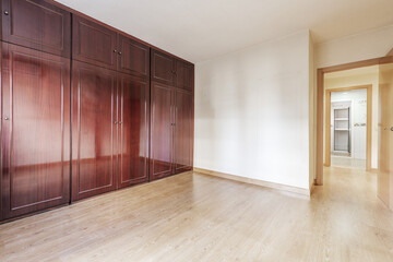 An empty room with a five body glossy mahogany wardrobe with oak hardwood floors