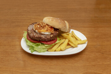 A great and delicious beef burger with home fries, goat cheese with crispy onion, tomato slices and lettuce leaves