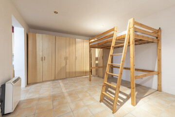 Room with a pine wood frame with stairs and box spring for a raised bed and a wall covered with wooden cabinets