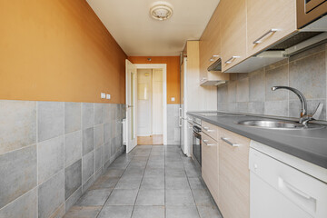 kitchen with light wood cabinets with gray countertops, white appliances and square tiles on half walls and floors
