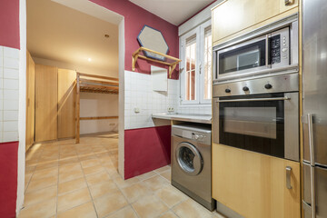 Corner of a kitchen furnished with stainless steel appliances and access to a living room without a door