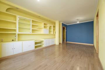 Empty room with oak floor, indigo blue wall and light yellow brick bookcase