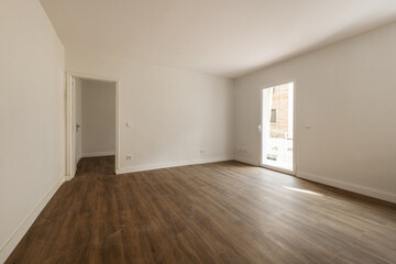 Empty room with dark wooden floors and access doors to other rooms and terrace with glass door.