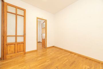 An empty room with several pine wood doors with windows and weathered oak flooring