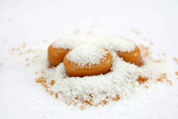 milk caramel candy and heap of sugar on white background