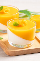 Delicious double colored mango panna cotta mousse pudding on wooden table background.