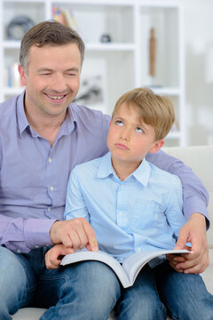 Father and son reading, child rolling eyes
