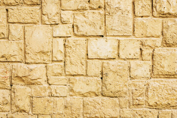 Yelow brick wall. Horizontal decorative uneven blocks background. Urban architecture texture. Solid stone texture. Grunge brickwork structure.