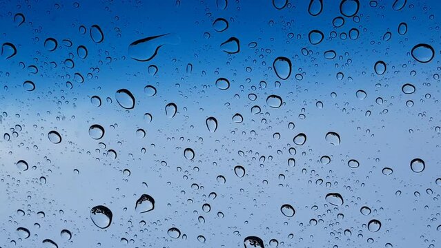 Water droplets perspective through glass surface against blue sky good for multimedia content backgrounds
