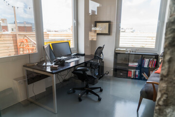 Shot of an empty desk and seat in a coworking space .