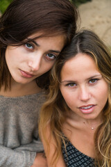 One brunette and one blonde couple of girls looking at camera in a serious way.